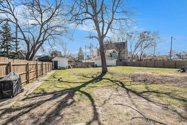 view of yard with an outbuilding, a storage unit, and a fenced backyard