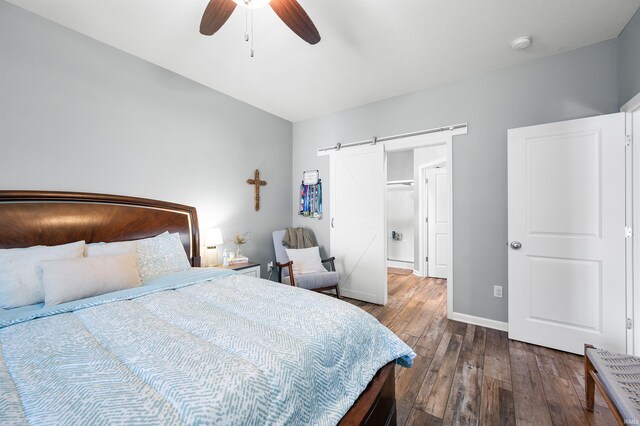 bedroom with baseboards, a barn door, ceiling fan, and wood-type flooring