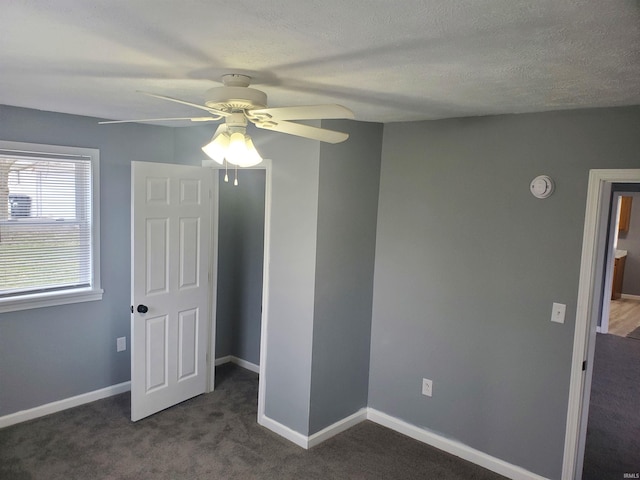 unfurnished bedroom featuring baseboards, dark colored carpet, and ceiling fan