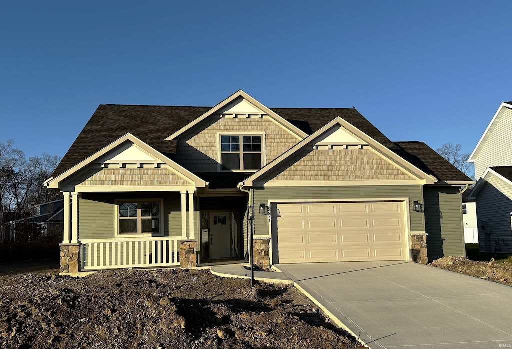 13941 Escondida Cv, Fort Wayne, IN 46845 - craftsman house with driveway, an attached garage, stone siding, and a porch