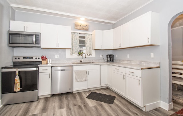 908 S Main St, Kendallville, IN 46755 - kitchen with white cabinets, light wood-style flooring, stainless steel appliances, arched walkways, and a sink