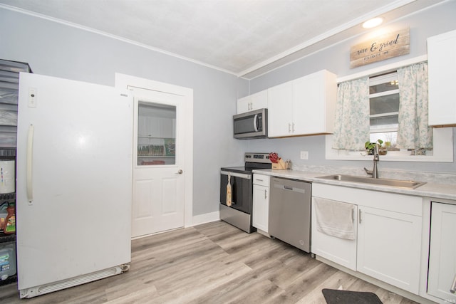 908 S Main St, Kendallville, IN 46755 - kitchen featuring light countertops, light wood-style flooring, a sink, white cabinets, and appliances with stainless steel finishes