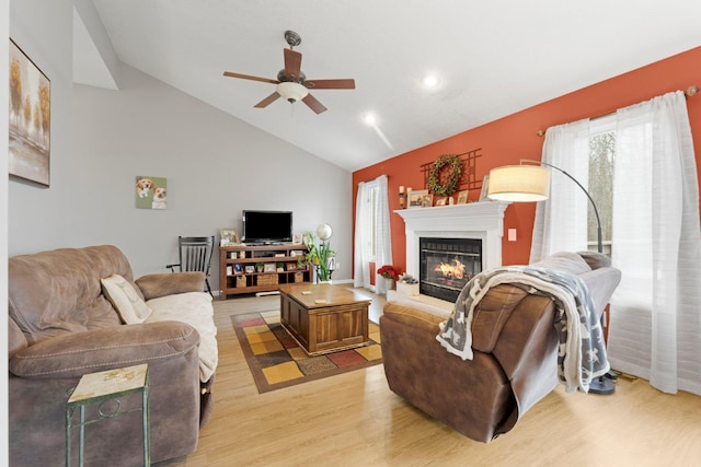 living area with vaulted ceiling, a ceiling fan, a glass covered fireplace, light wood-type flooring, and recessed lighting