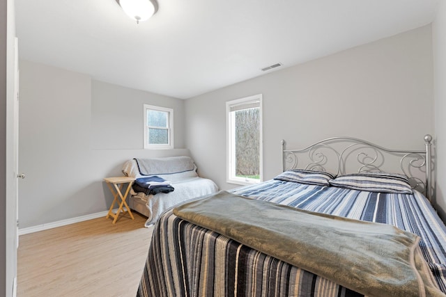 bedroom featuring baseboards, visible vents, and wood finished floors