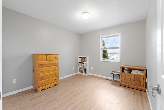 miscellaneous room featuring baseboards, light wood-type flooring, and a textured ceiling