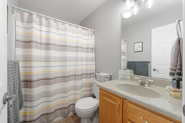 bathroom featuring a textured ceiling, toilet, vanity, and a shower with curtain