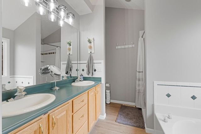 full bathroom featuring a tub, a sink, double vanity, and wood finished floors