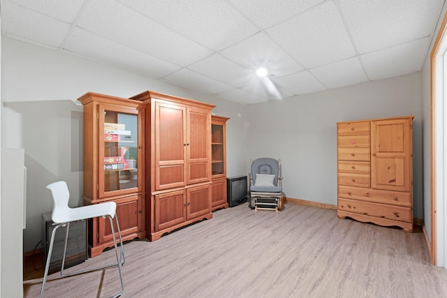 sitting room featuring a paneled ceiling, baseboards, and light wood-type flooring