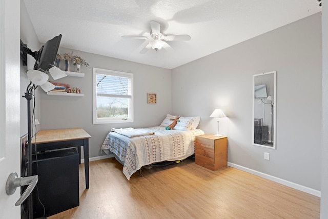 bedroom featuring baseboards, light wood-style flooring, and a ceiling fan