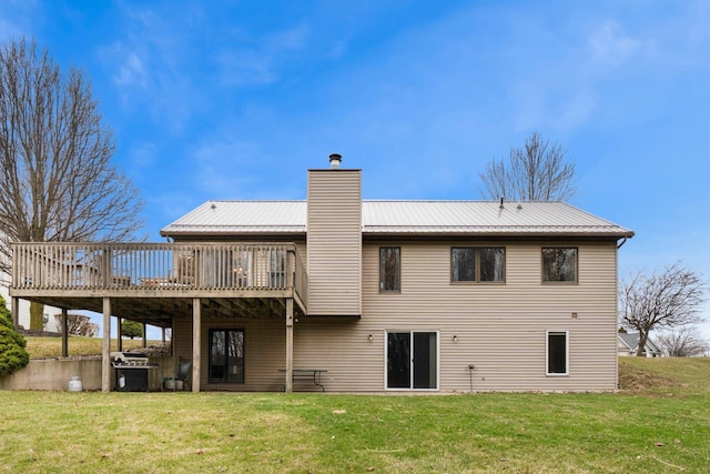 rear view of house featuring metal roof, a chimney, a wooden deck, and a yard