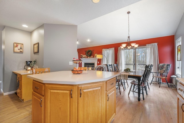 kitchen featuring a center island, a lit fireplace, light countertops, and light wood-style flooring