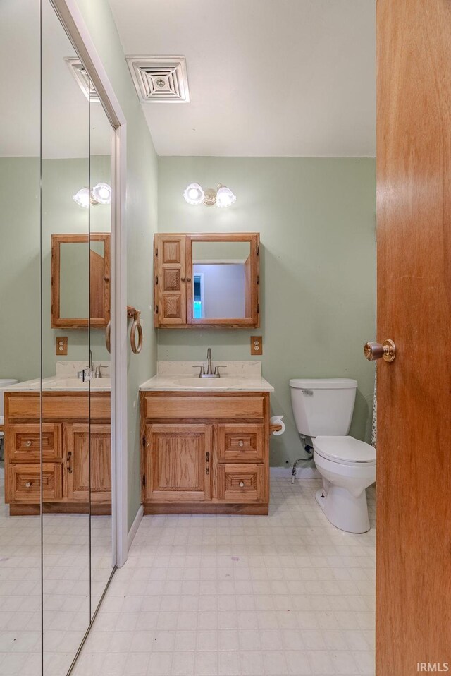 bathroom with tile patterned floors, vanity, toilet, and visible vents