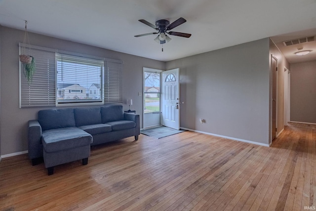 living room with baseboards, light wood-style floors, ceiling fan, and visible vents