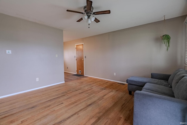 living area featuring baseboards, ceiling fan, visible vents, and light wood-type flooring