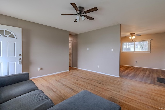 living room with baseboards, light wood-style floors, and a ceiling fan
