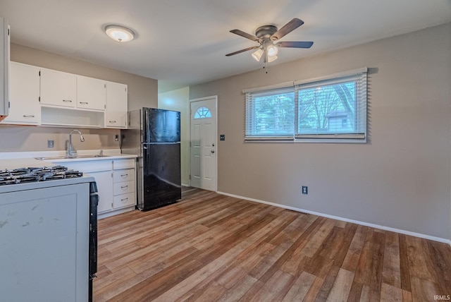 kitchen featuring a ceiling fan, a sink, light wood-type flooring, freestanding refrigerator, and gas range oven