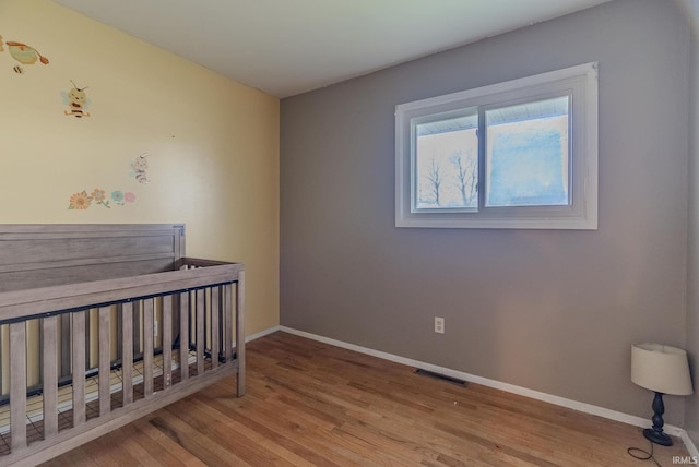 bedroom with baseboards, visible vents, and wood finished floors