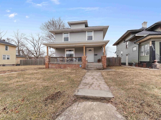 american foursquare style home featuring a front lawn, fence, and a porch