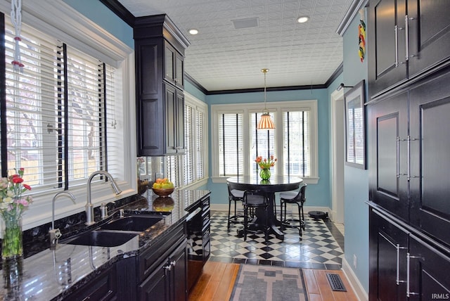 kitchen featuring baseboards, visible vents, a sink, crown molding, and dark stone countertops