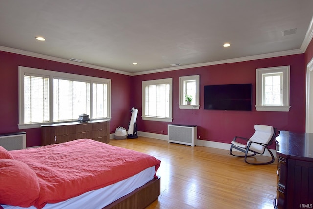 bedroom with ornamental molding, multiple windows, light wood finished floors, and radiator heating unit