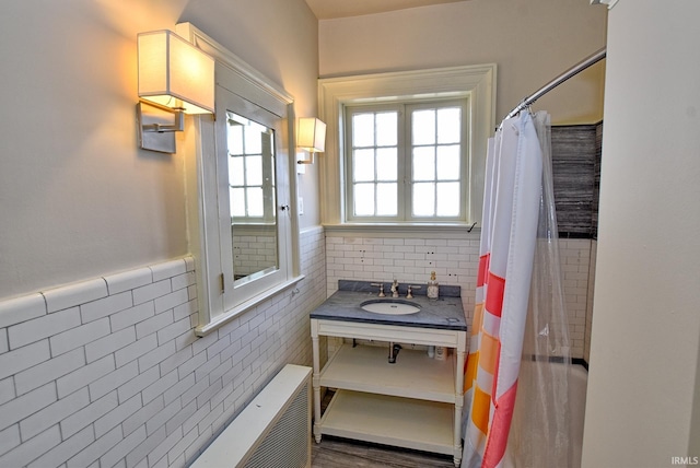 full bathroom with a shower with curtain, tile walls, vanity, and a wainscoted wall