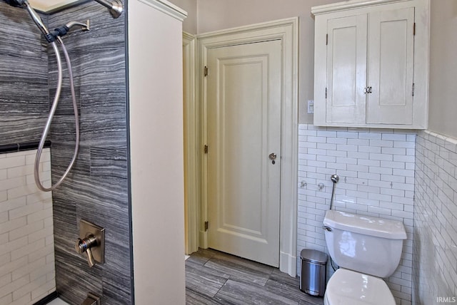 bathroom featuring tile walls, toilet, and a tile shower