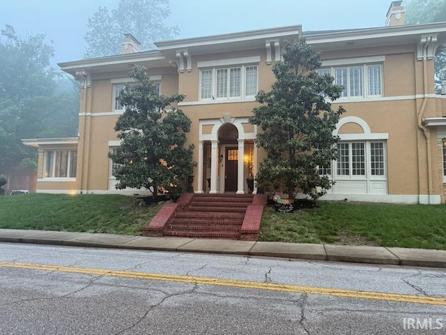 view of front of house with a front lawn, stucco siding, and a chimney