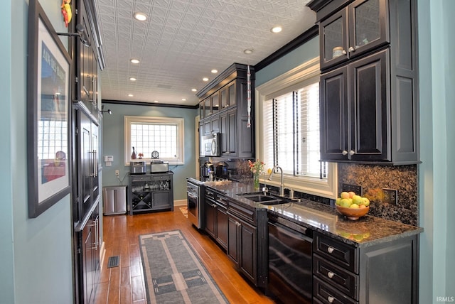 kitchen featuring visible vents, stainless steel microwave, a sink, wood finished floors, and tasteful backsplash