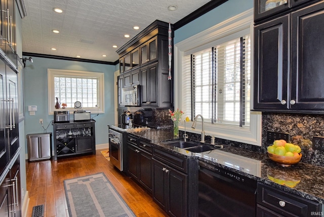 kitchen with a sink, stainless steel microwave, dark stone countertops, black dishwasher, and backsplash