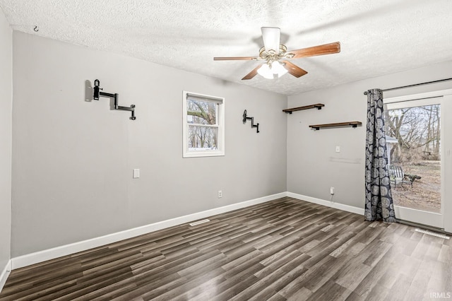unfurnished room featuring a textured ceiling, dark wood-type flooring, healthy amount of natural light, baseboards, and a ceiling fan