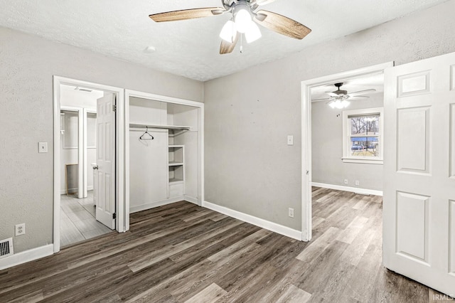 unfurnished bedroom with wood finished floors, a textured wall, baseboards, ceiling fan, and a textured ceiling