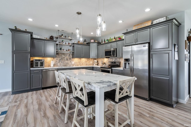 kitchen featuring decorative backsplash, appliances with stainless steel finishes, decorative light fixtures, open shelves, and a center island