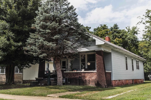 view of side of home with a chimney, a porch, and a lawn