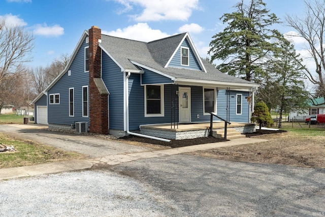 view of front of house with a porch, a garage, a chimney, aphalt driveway, and central air condition unit