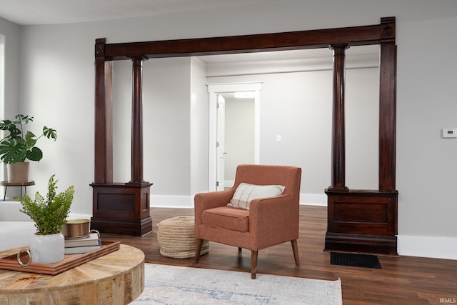 living area with visible vents, baseboards, decorative columns, and wood finished floors