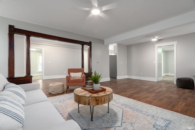 living room featuring baseboards, a ceiling fan, and wood finished floors