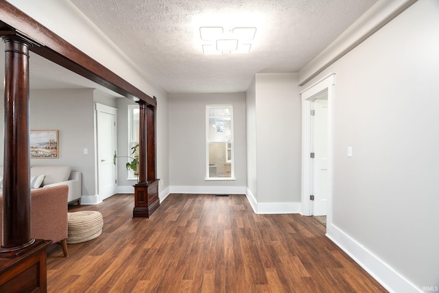 hallway with a textured ceiling, baseboards, and dark wood finished floors