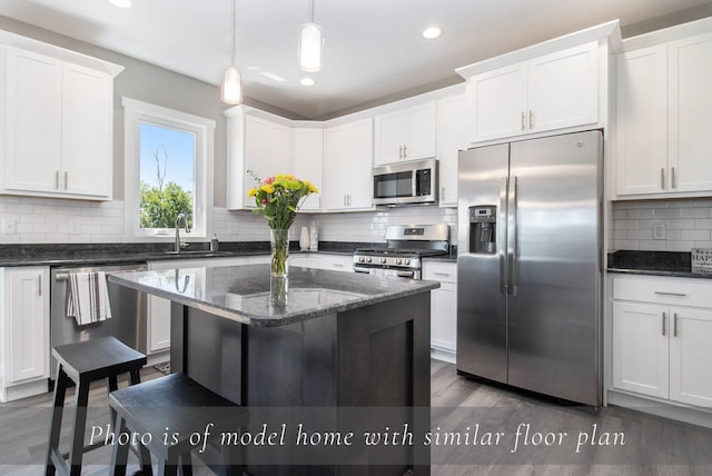 kitchen featuring dark stone countertops, white cabinetry, backsplash, appliances with stainless steel finishes, and hanging light fixtures
