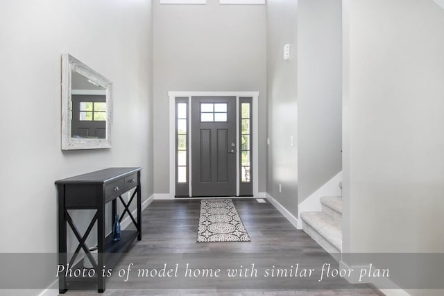entryway featuring baseboards, stairway, a high ceiling, and wood finished floors