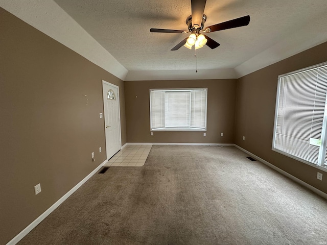 unfurnished room featuring light carpet, a ceiling fan, visible vents, and a wealth of natural light