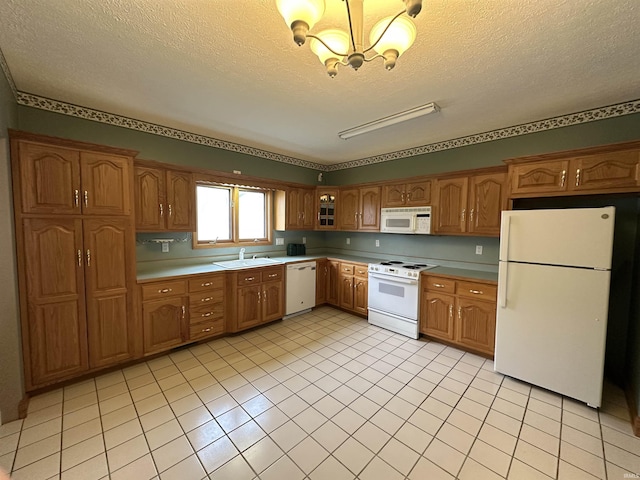 kitchen with a notable chandelier, white appliances, a sink, and a textured ceiling
