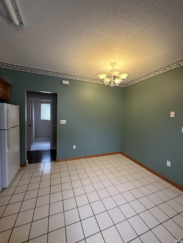 spare room with baseboards, a textured ceiling, a chandelier, and light tile patterned floors