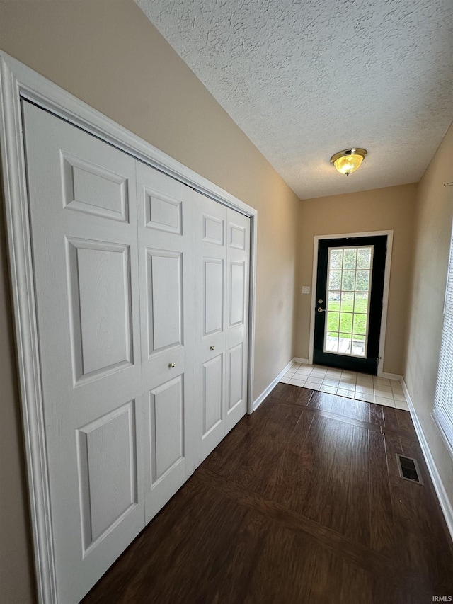 entryway featuring baseboards, wood finished floors, visible vents, and a textured ceiling