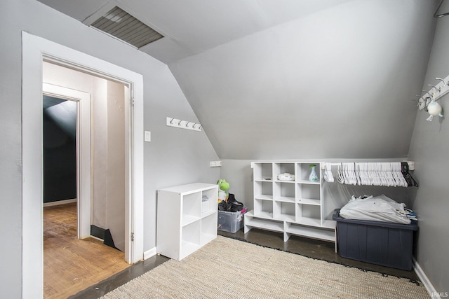 interior space featuring wood finished floors, lofted ceiling, and visible vents