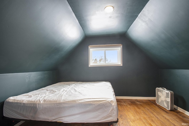 bedroom with baseboards, vaulted ceiling, and wood finished floors