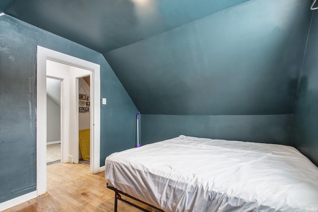 bedroom featuring baseboards, vaulted ceiling, and wood finished floors
