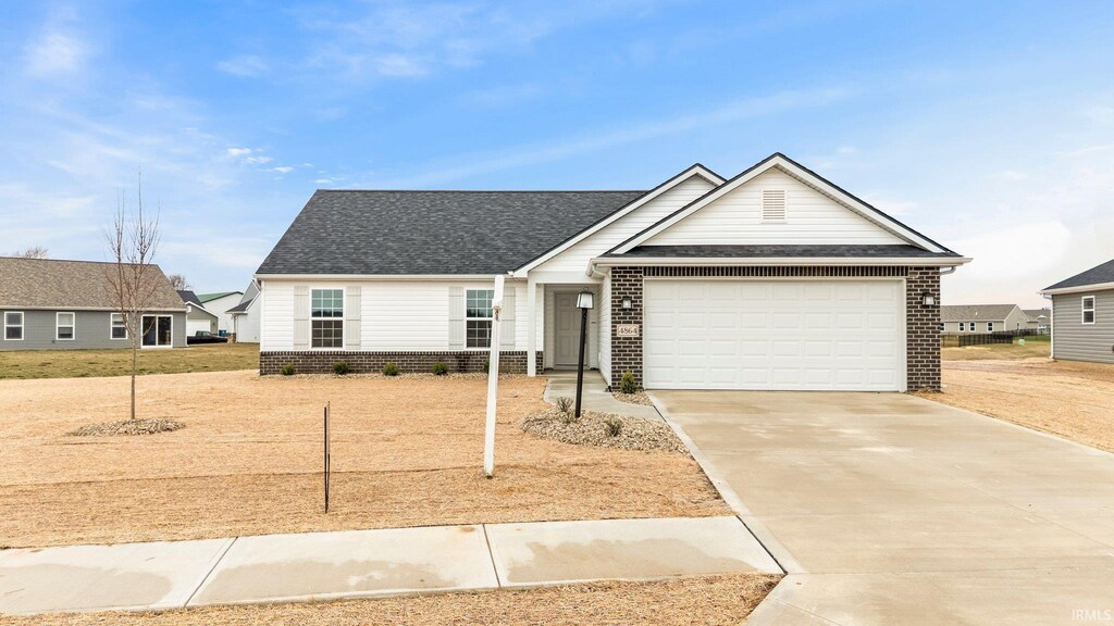 single story home featuring brick siding, concrete driveway, a shingled roof, and an attached garage