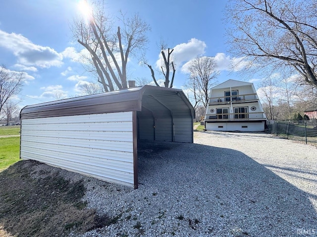 view of outdoor structure with a detached carport, fence, and gravel driveway