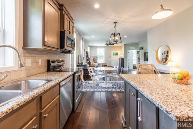 kitchen with open floor plan, stainless steel appliances, a sink, a ceiling fan, and brown cabinets