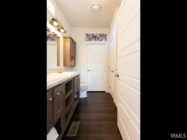 bathroom featuring toilet, vanity, wood finished floors, and visible vents